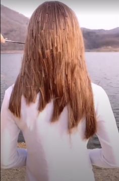 a woman with long hair standing by the water