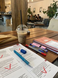 a cup of coffee sitting on top of a table next to notebooks and papers