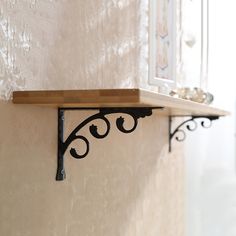 the shelf is made out of wood and has wrought iron brackets on each side, along with a glass window