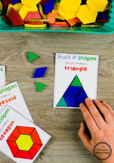 two hands are holding colorful shapes on the table