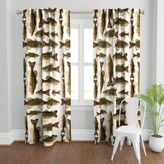 a white chair sitting in front of a window covered in fish curtain panels and valances