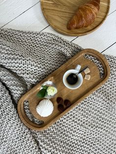 a wooden tray with coffee and croissants on it next to a plate