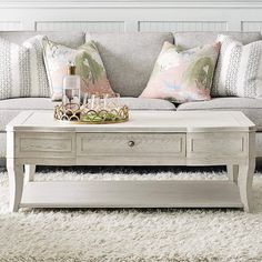 a living room with a couch, coffee table and pillows on the carpeted floor