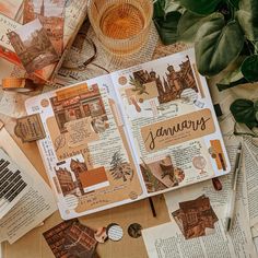 an open book sitting on top of a table covered in papers and other items next to a cup