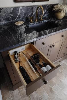 an open drawer in the middle of a kitchen counter with utensils and other items