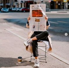 a person sitting in a chair reading a newspaper