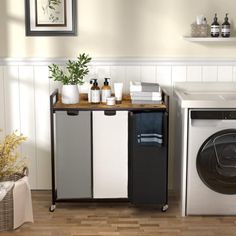 a washer sitting next to a dryer in a room with white walls and wooden floors