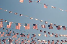 several american flags are hanging on a line with colors in the sky and below them