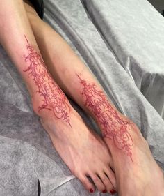 a woman's legs with tattoos on them and red ink in the shape of flowers