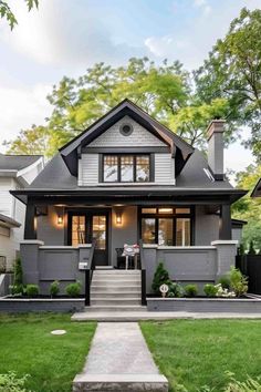 a gray house with white trim and black shutters on the front door is shown