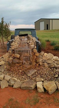 a truck is parked in front of a rock wall with a water feature on it