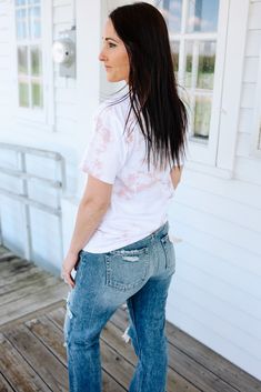 a woman standing on a porch with her back to the camera, wearing jeans and a white t - shirt