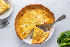 a quiche on a plate with a slice cut out and salad in the background