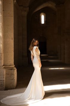 a woman in a white wedding dress is posing for the camera with her back to the camera