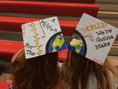 two girls wearing graduation caps with writing on them