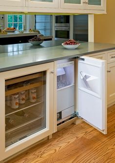 an open refrigerator in a kitchen with white cabinets