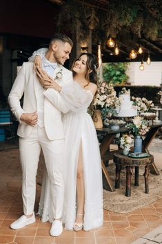 a man and woman standing next to each other in front of a table with flowers