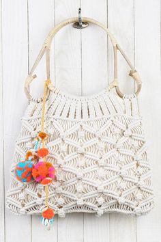 a crocheted purse hanging on the wall with an orange pom pom