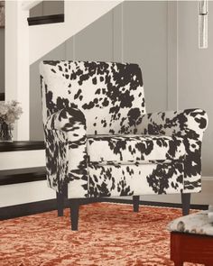 a cow print chair sitting on top of a rug in front of a stair case