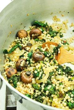 mushrooms and spinach are being cooked in a pan