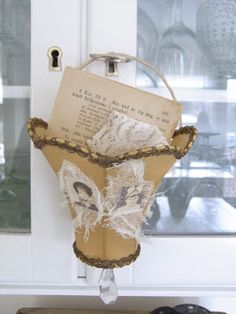 an old book is hanging on the front door with lace and pearls attached to it