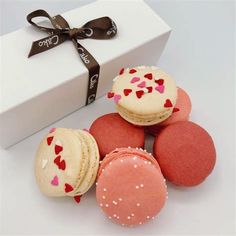 four macaroons are sitting next to a white box