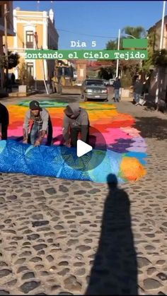 three men working on a colorful mural in the street