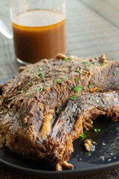 a black plate topped with meat next to a cup of sauce