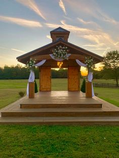 a gazebo decorated with flowers and greenery at sunset