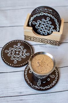 a cup of coffee sitting on top of a wooden table next to two coasters