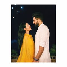 a man and woman standing next to each other in front of a dark sky at night