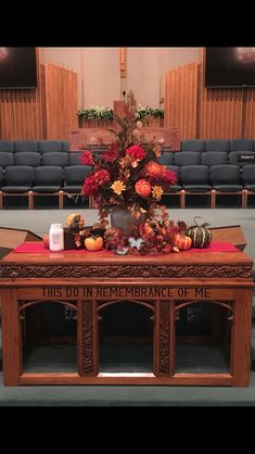 a wooden table with flowers and candles on it in front of an empty auditorium filled with seats