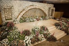 an elaborately decorated stage with flowers and greenery on the sides for a wedding ceremony