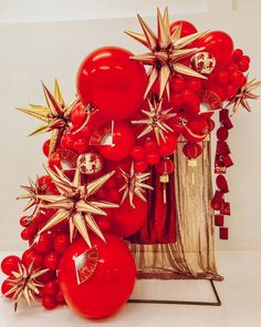 an arrangement of red and gold ornaments in front of a white backdrop with starbursts