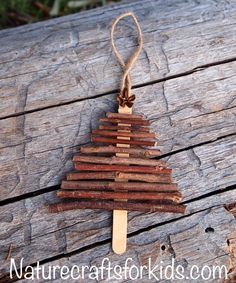 a popsicle shaped christmas tree ornament made out of wood sticks on a piece of wood