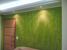 a room with a bed and a green wall in the corner that has grass growing on it