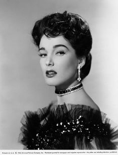 an old black and white photo of a woman with short hair wearing a feathered dress