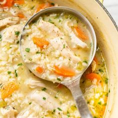 a ladle filled with chicken and rice soup