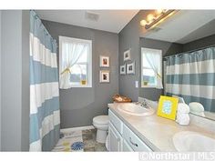 a bathroom with blue and white striped shower curtain next to a sink, toilet and mirror