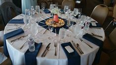 the table is set with silverware and blue napkins for an elegant dinner party