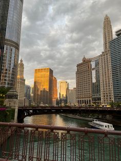 a boat traveling down a river next to tall buildings in a city at sunset or dawn