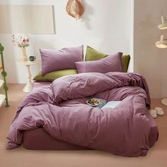 a bed covered in purple sheets and pillows