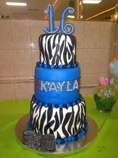 a three tiered cake with zebra print and blue icing is on a table