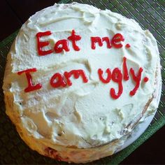 a cake with the words eat me, i am ugly written on it in red