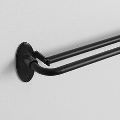 two black towel racks mounted on the wall next to each other, with one hanging from it's side