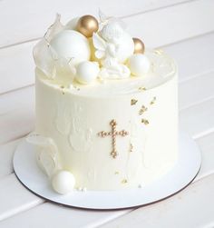 a white cake with gold decorations and a cross on the top is sitting on a plate