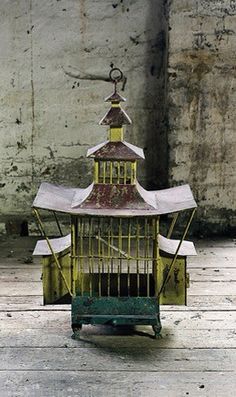 a yellow birdcage sitting on top of a wooden floor next to a wall