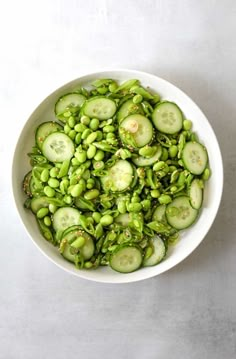 a white bowl filled with cucumbers and green beans on top of a table