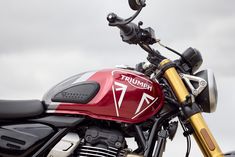 a red and black motorcycle parked on top of a street next to a cloudy sky