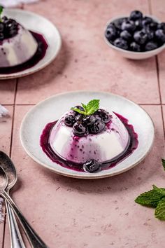 blueberry cheesecake on a plate with spoons next to it and other dessert items